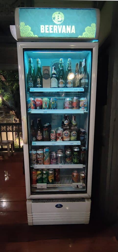 A Beervana branded beer fridge at Dok Kaew House bar in Bangkok Thailand. Bottles and cans of craft beer. 