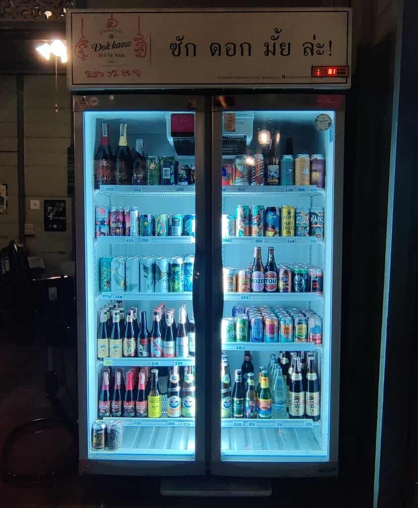 Beer fridge at Dok Kaew house bar in Bangkok. Various cans and bottles of local and imported craft beer.