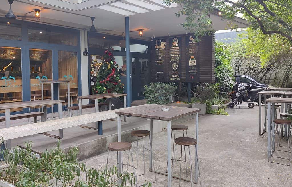 Front entrance of Mikkeller Bangkok, insludes tables and benches on the patio outside. 