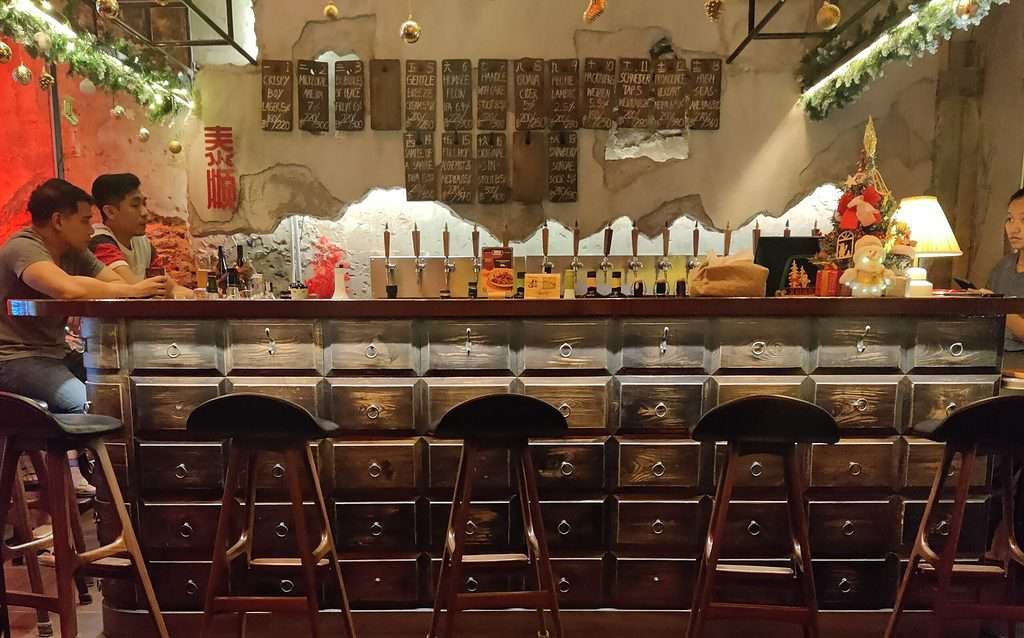 Tai Soon Bar with 21 taps. 5 bar stools open in front of the bar which is decorated with the old medicine boxes that were previously used in the location.