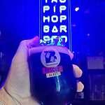 Glass of black IPA in front of Taopiphop's neon sign in Bangkok