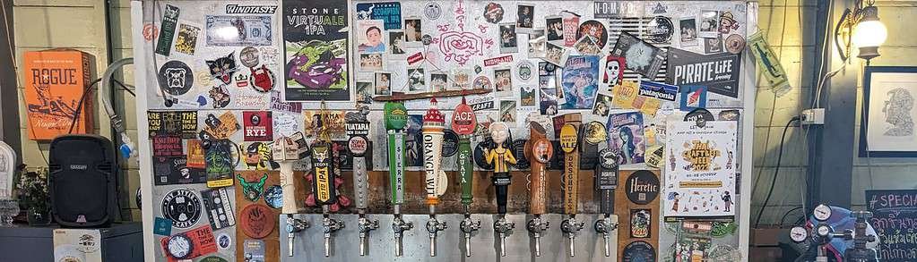 The tap wall at Dok Kaew House bar  in Bangkok Thailand. INcludes lots of stickers of breweries and other craft beers. 