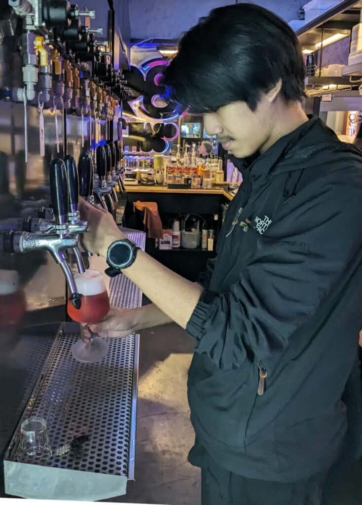 Bartender pouring a craft beer at 39 Craft Coffee in Bangkok Thailand