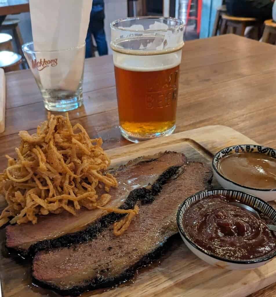 Rogue craft beer in a pint glass on a wooden table with brisket platter at Billy's Smokehouse Craft beer bar and barbeque