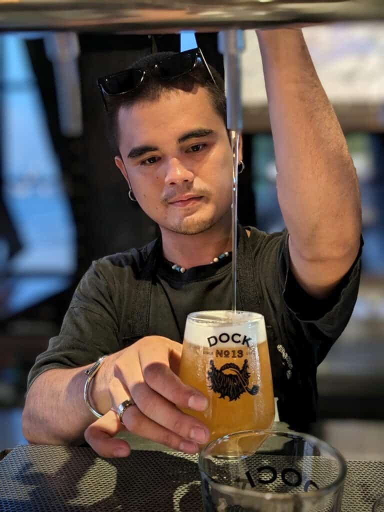 Staff pouring a glass of beer into a Dock No. 13 branded glass at Sheepshank Public house or Dock No. 13 in Bangkok, Thailand.