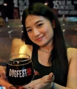 Bar staff smiling and serving a stout in a DOGFEST branded glass at Hair of the Dog craft beer bar in Bangkok Thailand.