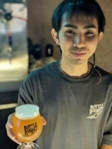 Bar man serving a goblet of thai craft beer at Bottle Rockets Beer bar in Bangkok Thailand.